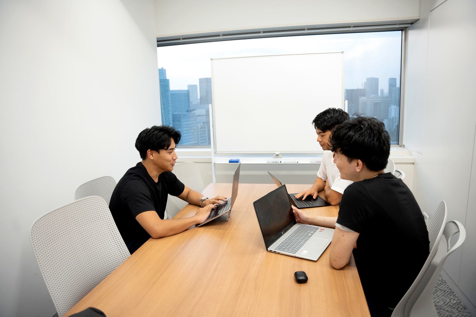 会議室で打ち合わせをするメンバー3人